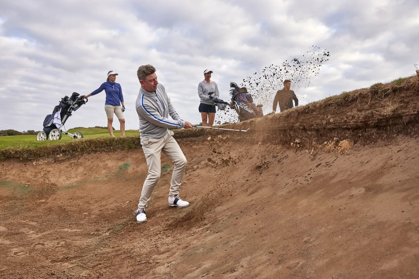 A golfer splashing out of a bunker at 13th Beach Golf Links