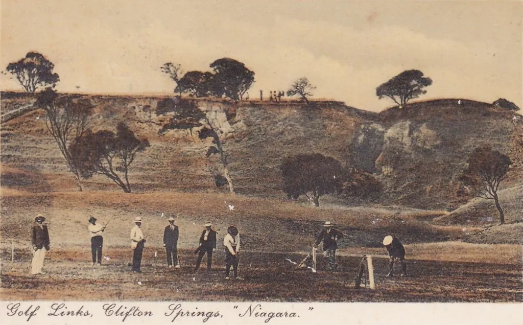 Hand-tinted 1911 postcard of golfers on the links at Clifton Springs below eroded clay cliffs