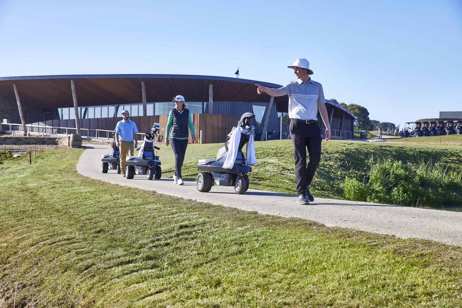 Golfers walking with buggies past the clubhouse at Curlewis Golf Club