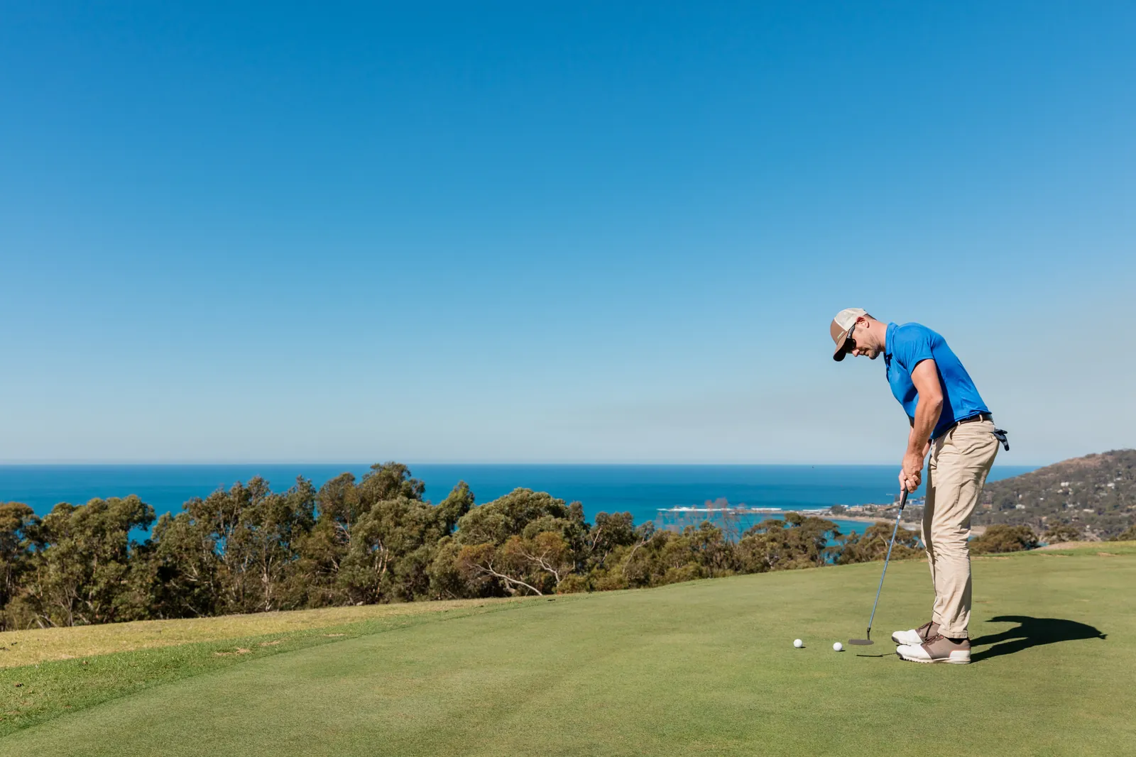 A golfer putting with the sea behind at Lorne Country Club