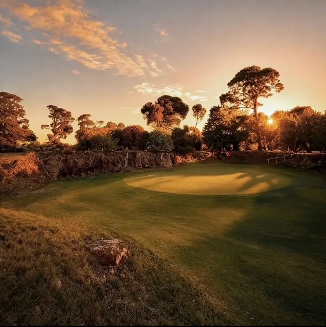 The quarry green at Winchelsea Golf Club at sunset, below a wall of bluestone with gums and pines along the rim
