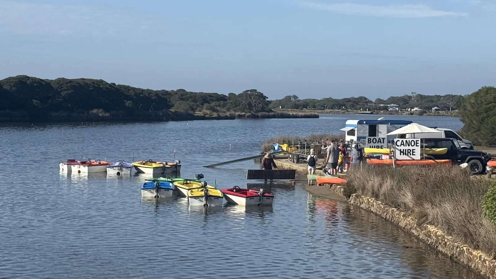 Paddle boats and fun boats lined up on the Anglesea River on a calm summer morning