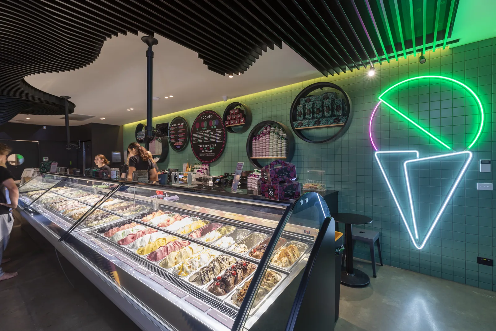 Inside the Torquay store: the long gelato cabinet and a neon ice cream cone on the tiled wall