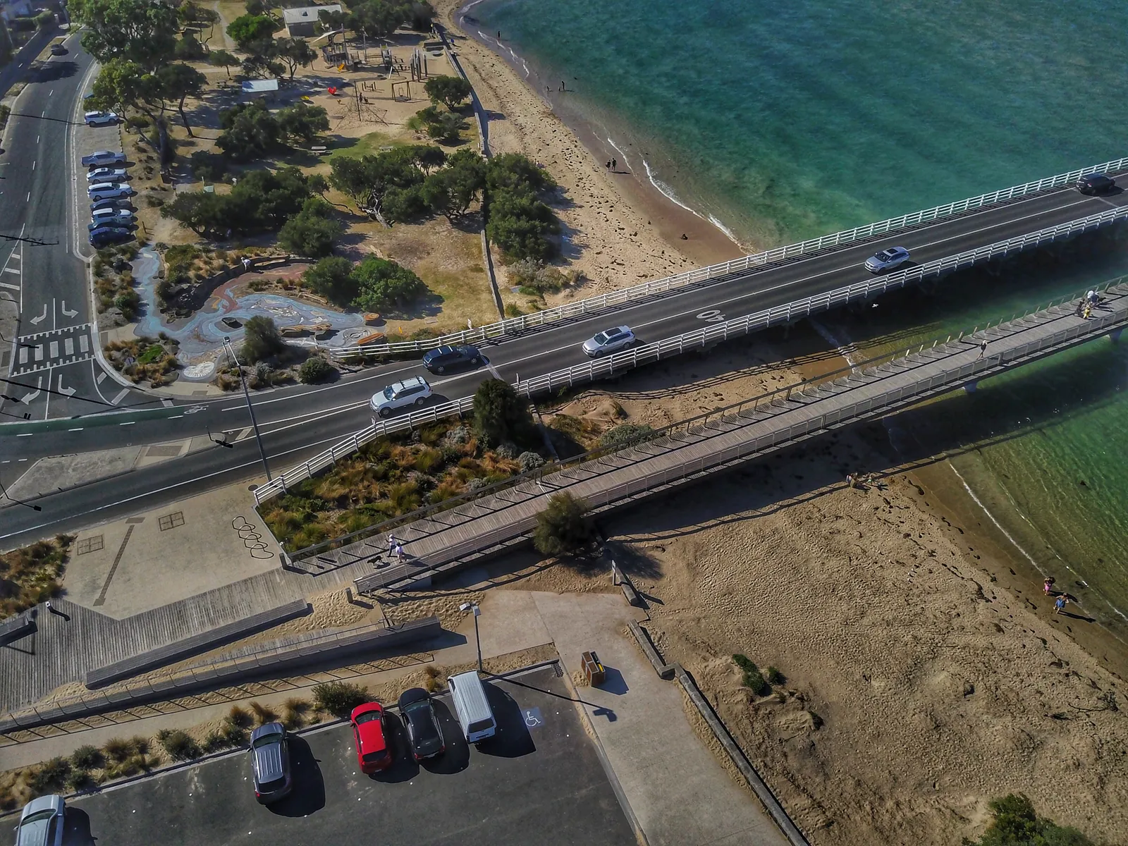 Aerial view of the Barwon Heads road bridge and the separate footbridge, with the riverside park and car park below
