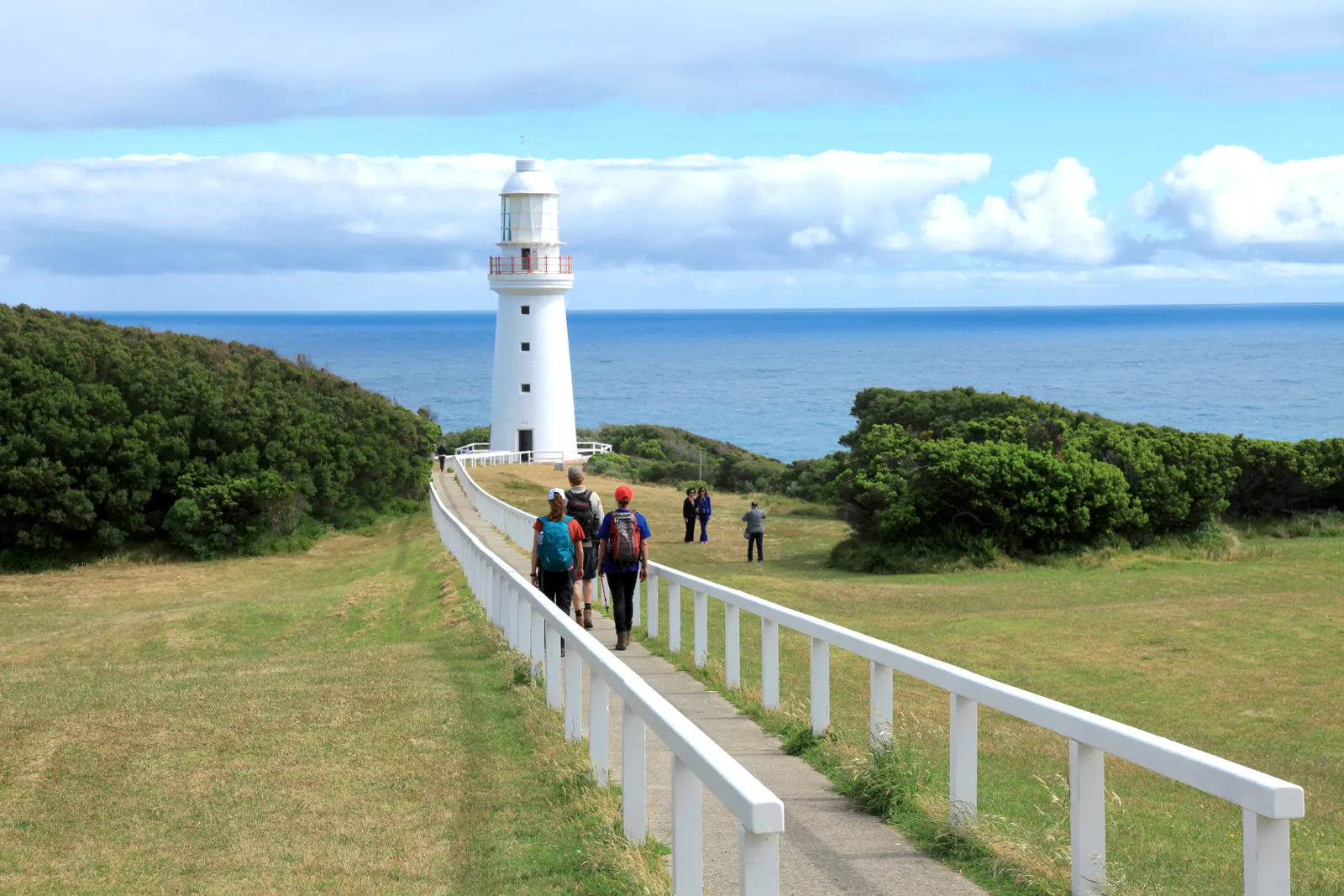 Cape Otway Lighthouse above the green headland, with visitors walking towards it