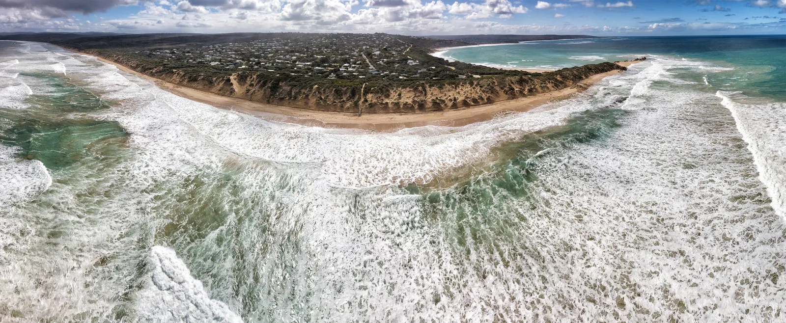 Aerial view of Point Roadknight near Anglesea, with surf rolling into the beach and the point curving out to sea