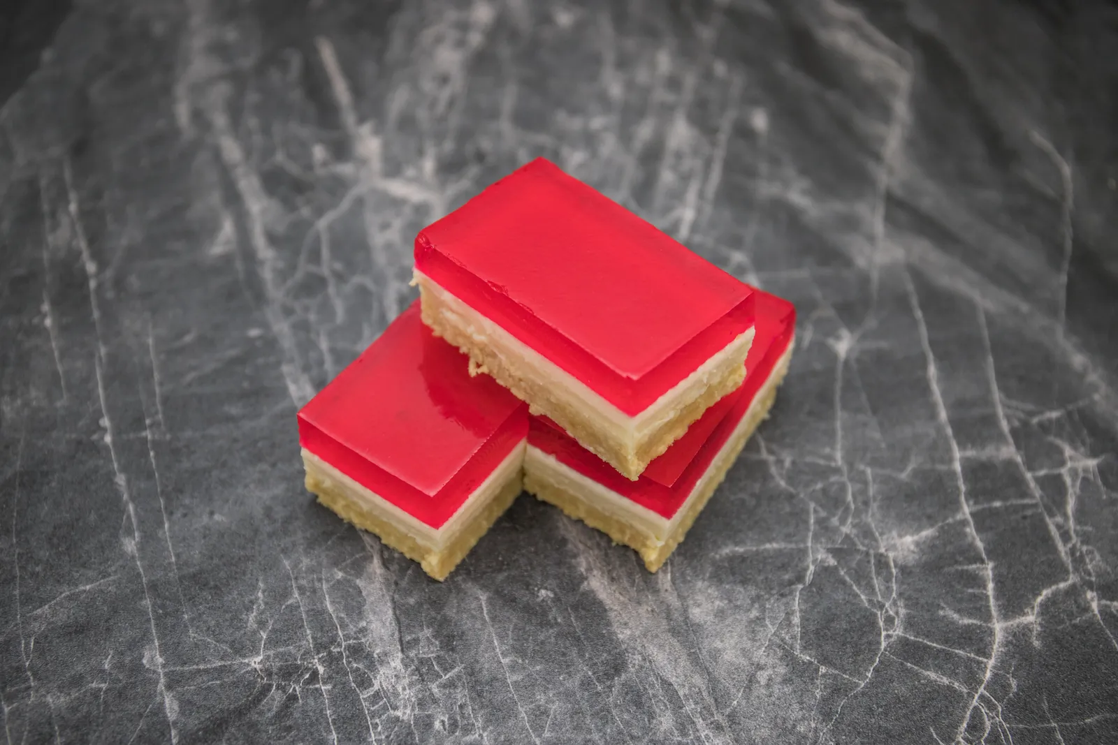 Pieces of red jelly slice stacked on dark marble