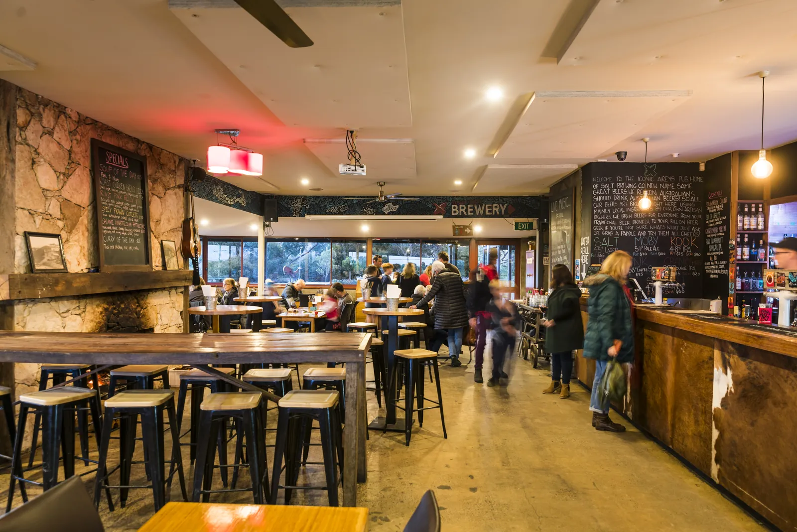 The long bar and dining room of the Aireys Pub, with high tables and the Brewery sign behind the bar