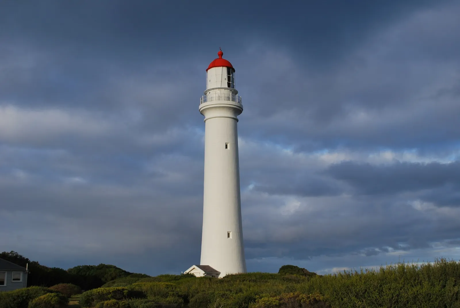 The white Split Point Lighthouse with its red cap under a stormy sky, Aireys Inlet