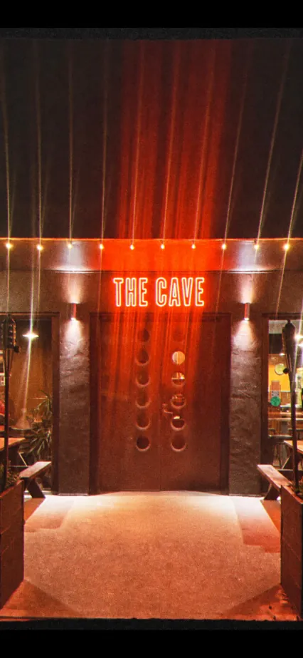 The lit sign and front door of The Cave Wood Fired Pizza in Jan Juc at night