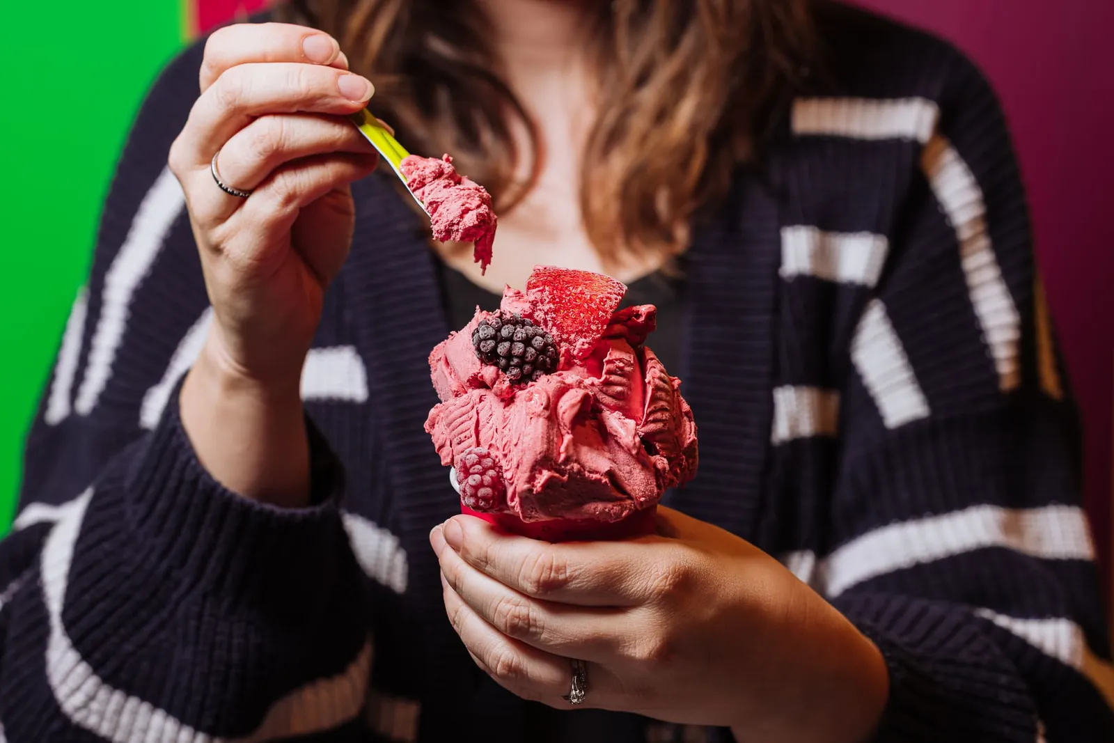 A cup of raspberry ice cream topped with fresh berries