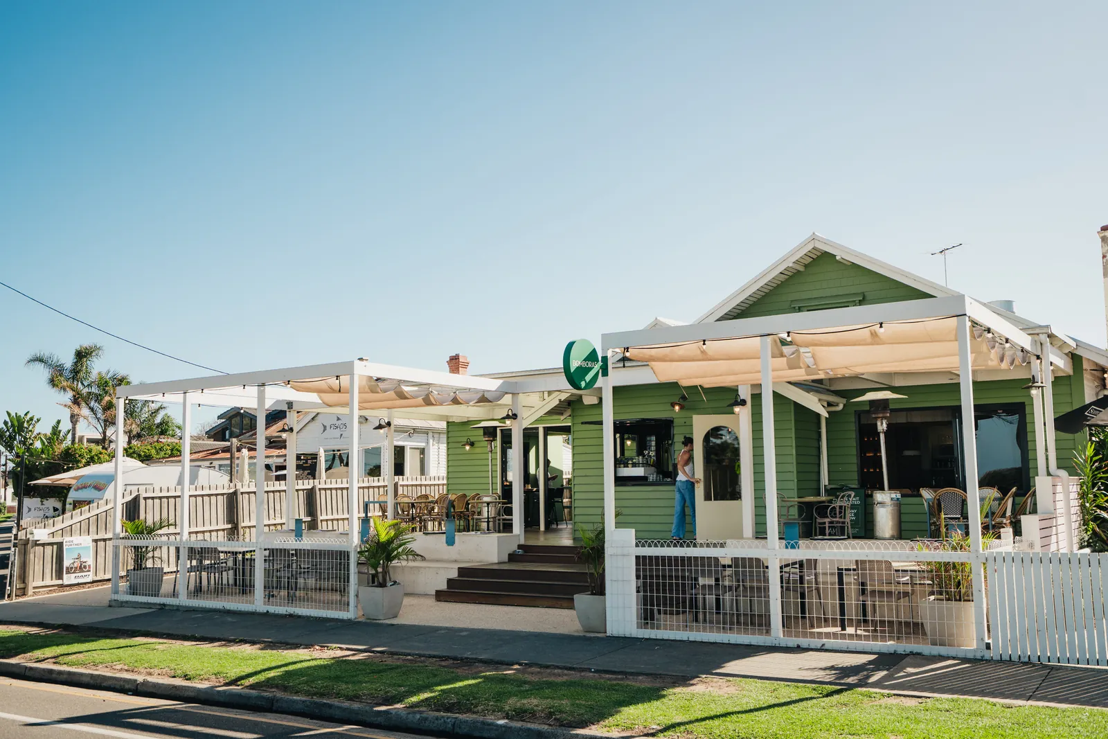 Bomboras, a green weatherboard cafe with a white pergola deck on The Esplanade, Torquay
