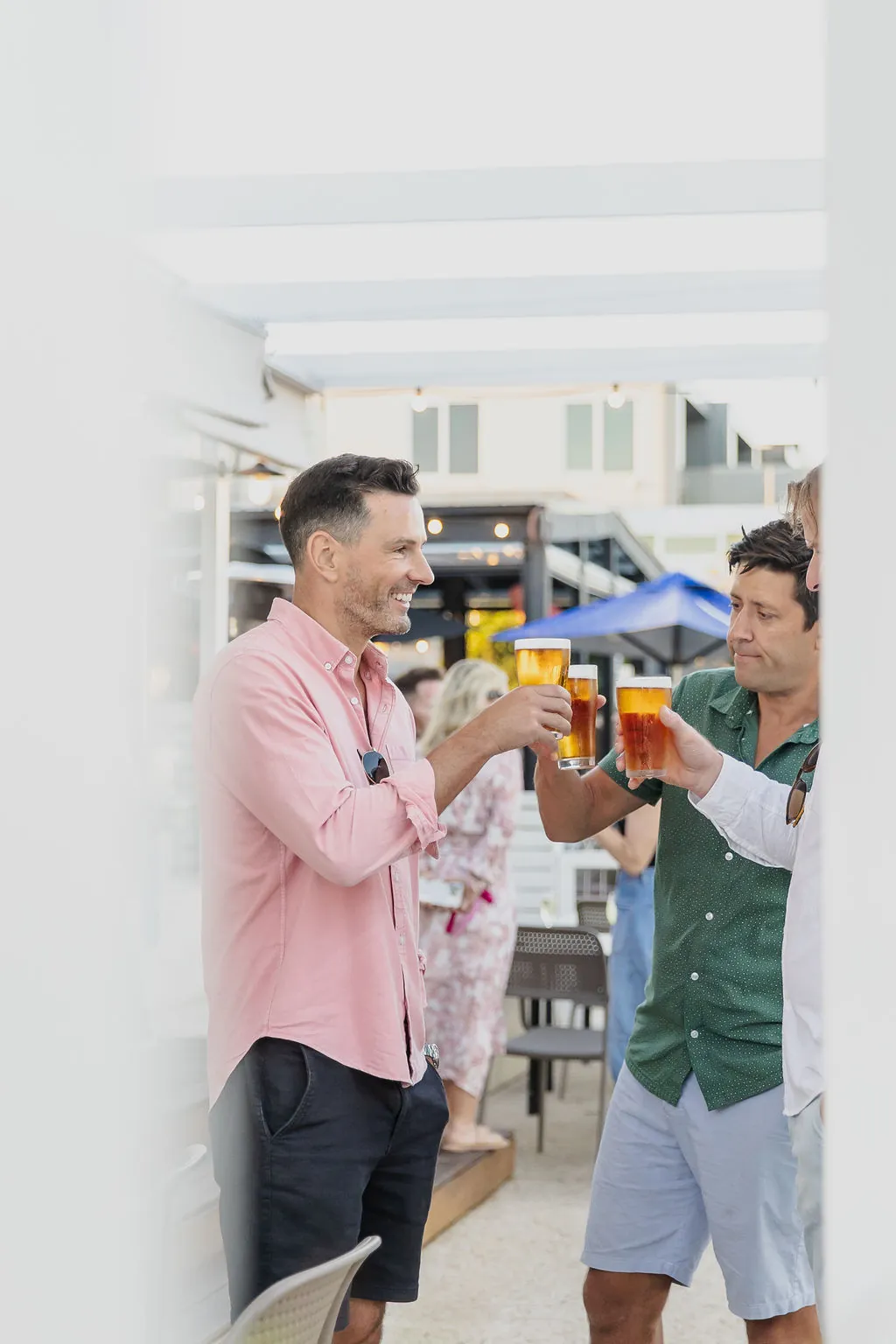 Two friends clinking beers on the deck at Bomboras