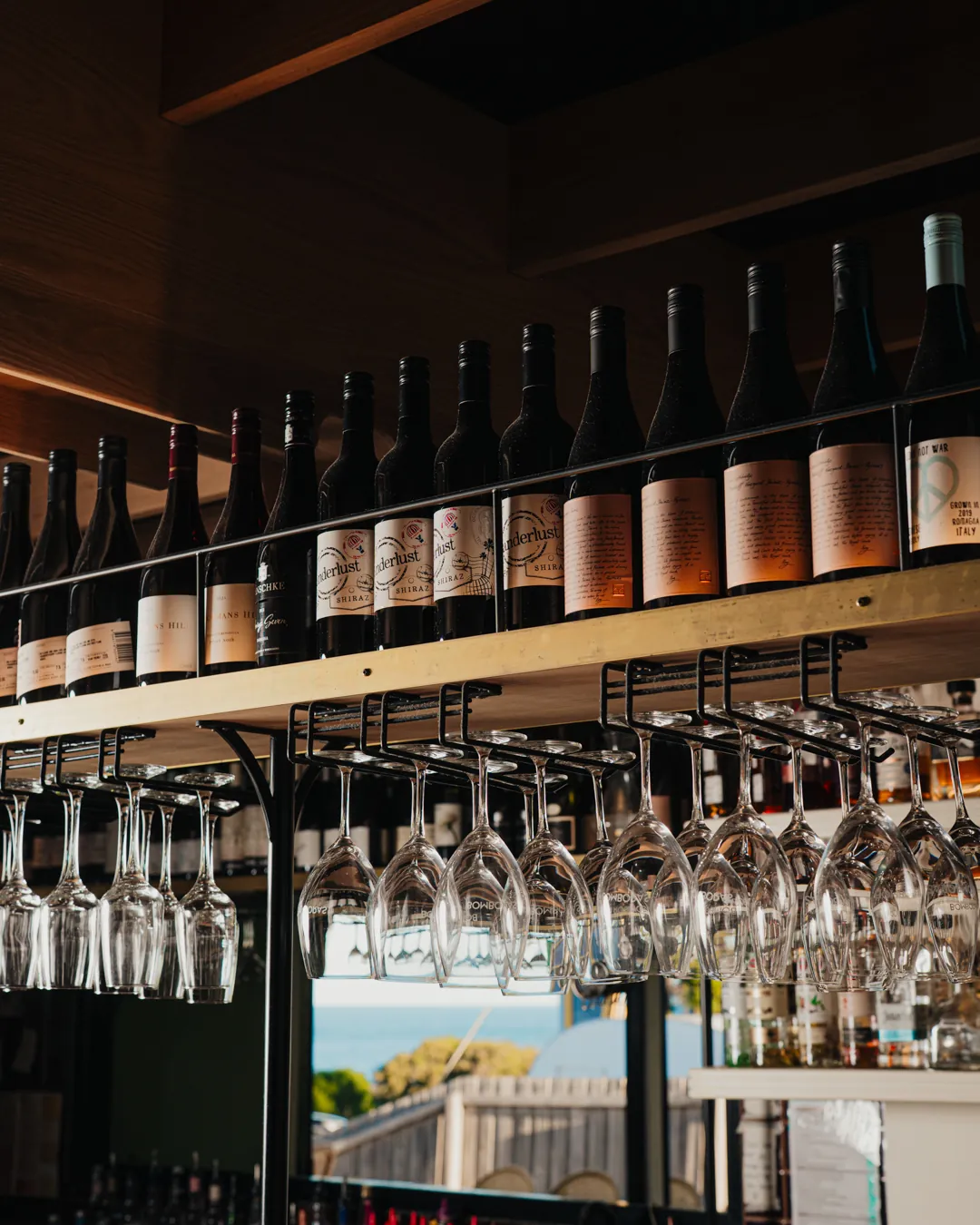 Wine bottles and hanging glasses above the bar at Bomboras