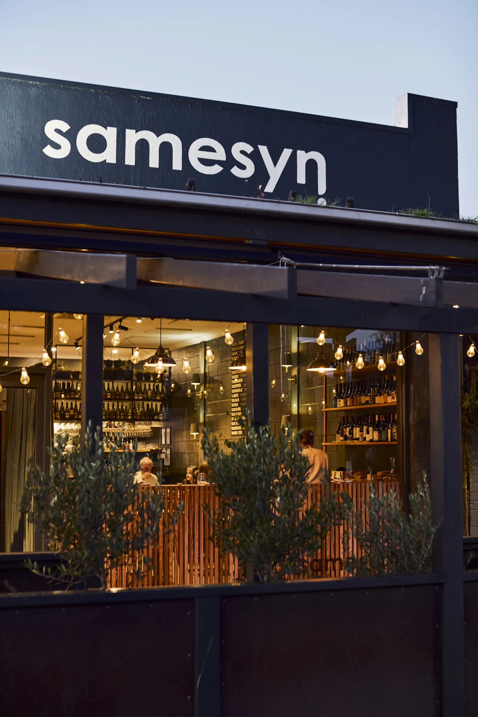 The Samesyn shopfront on Bell Street, Torquay, lit up at dusk