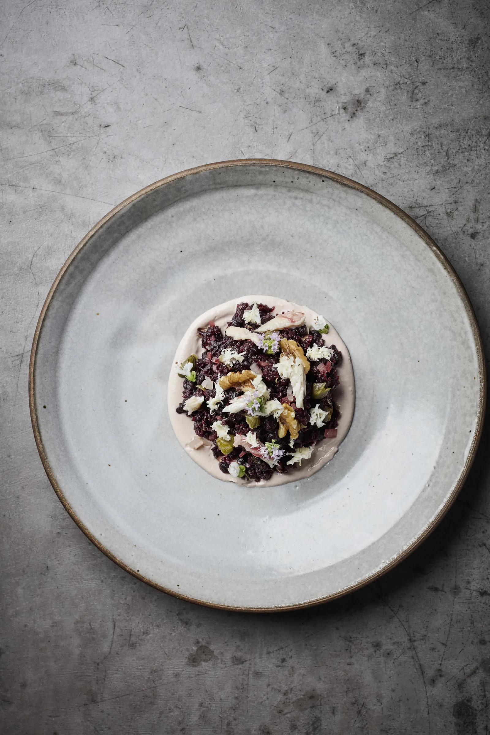 A small plated dish in the centre of a wide speckled ceramic plate