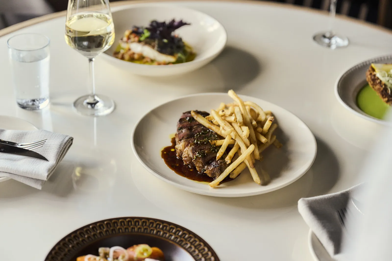 Steak with fries and jus at Surf Hotel, with a glass of white wine