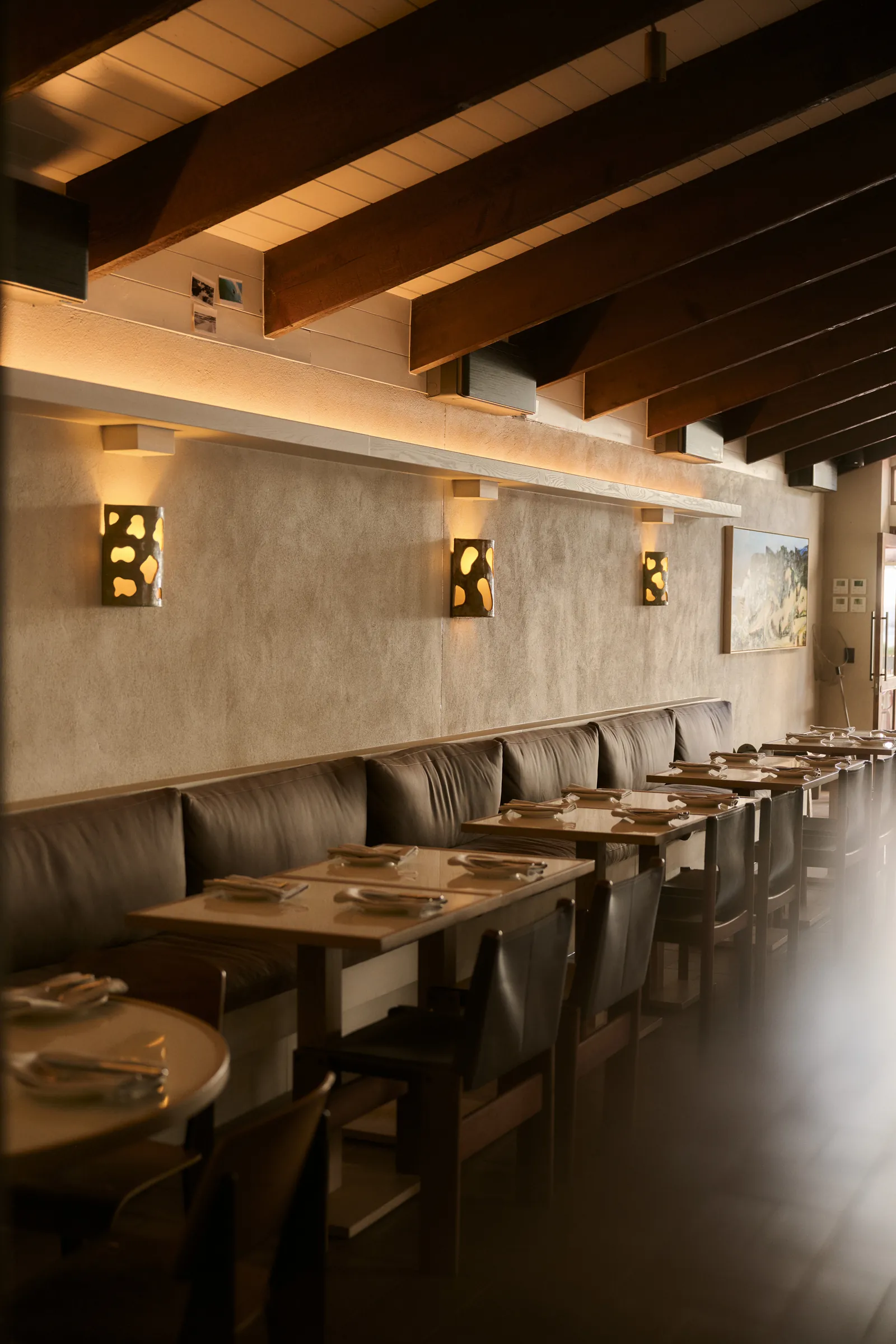 Leather banquettes and set tables under timber beams in the Surf Hotel dining room