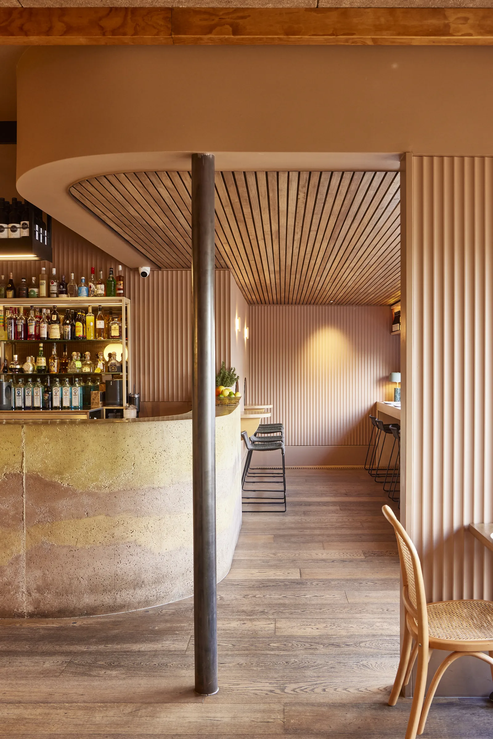 The curved bar at The Kyn with shelves of bottles